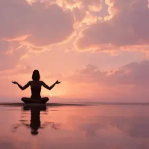 Silhouette femme méditant en lotus au coucher du soleil sur l'eau calme